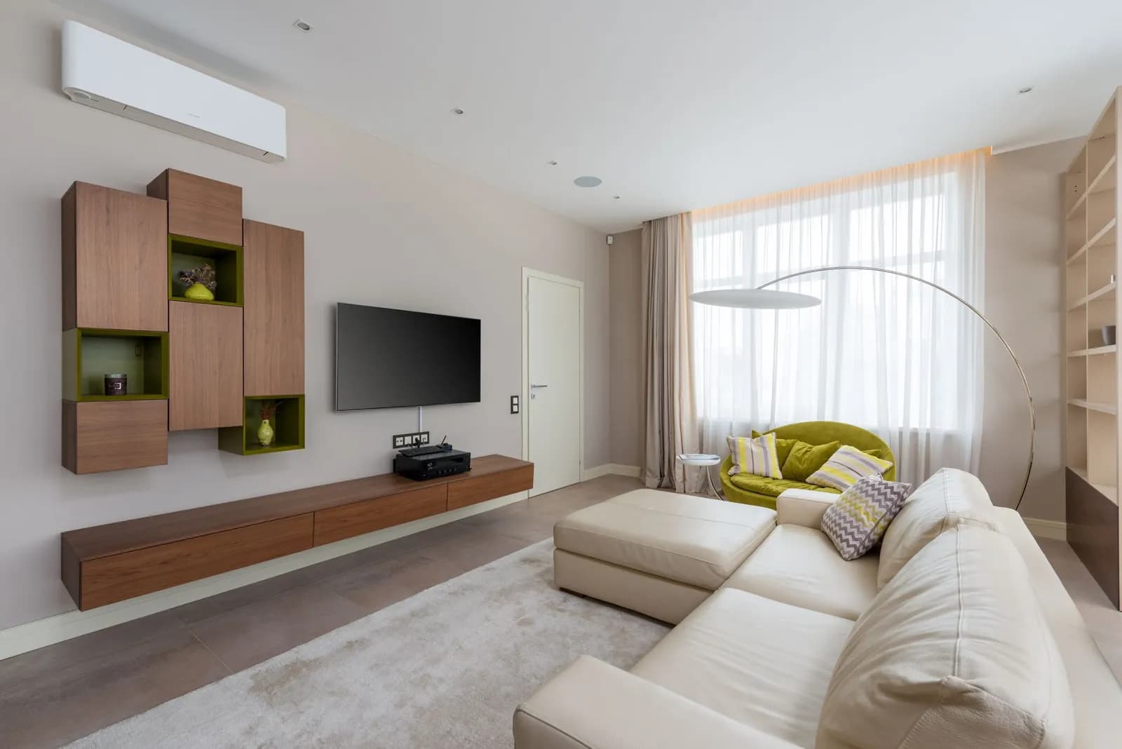 Bright living room with a wall-mounted split system air conditioner above a cream sofa